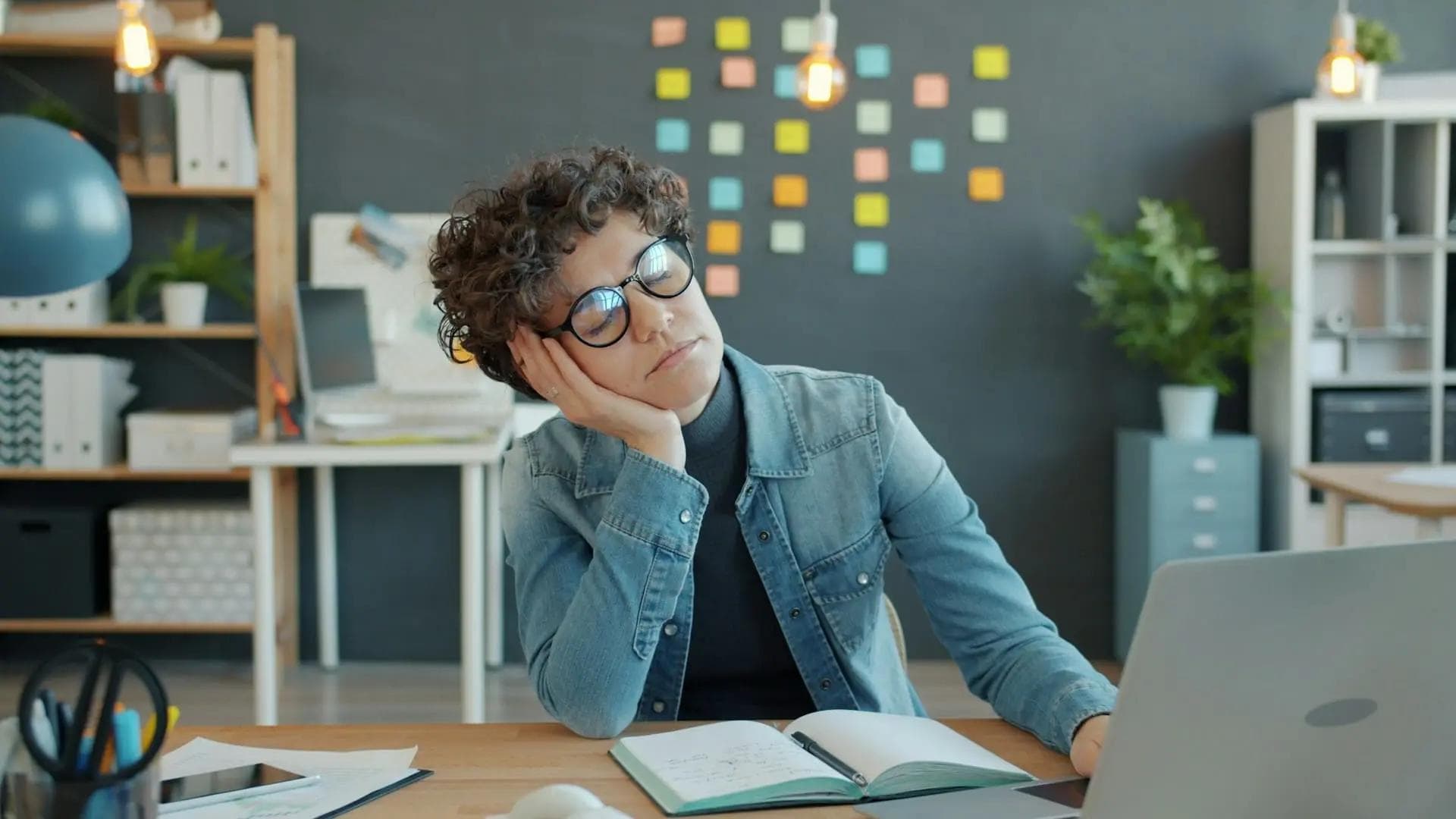 White woman resting head on her hand and napping at desk