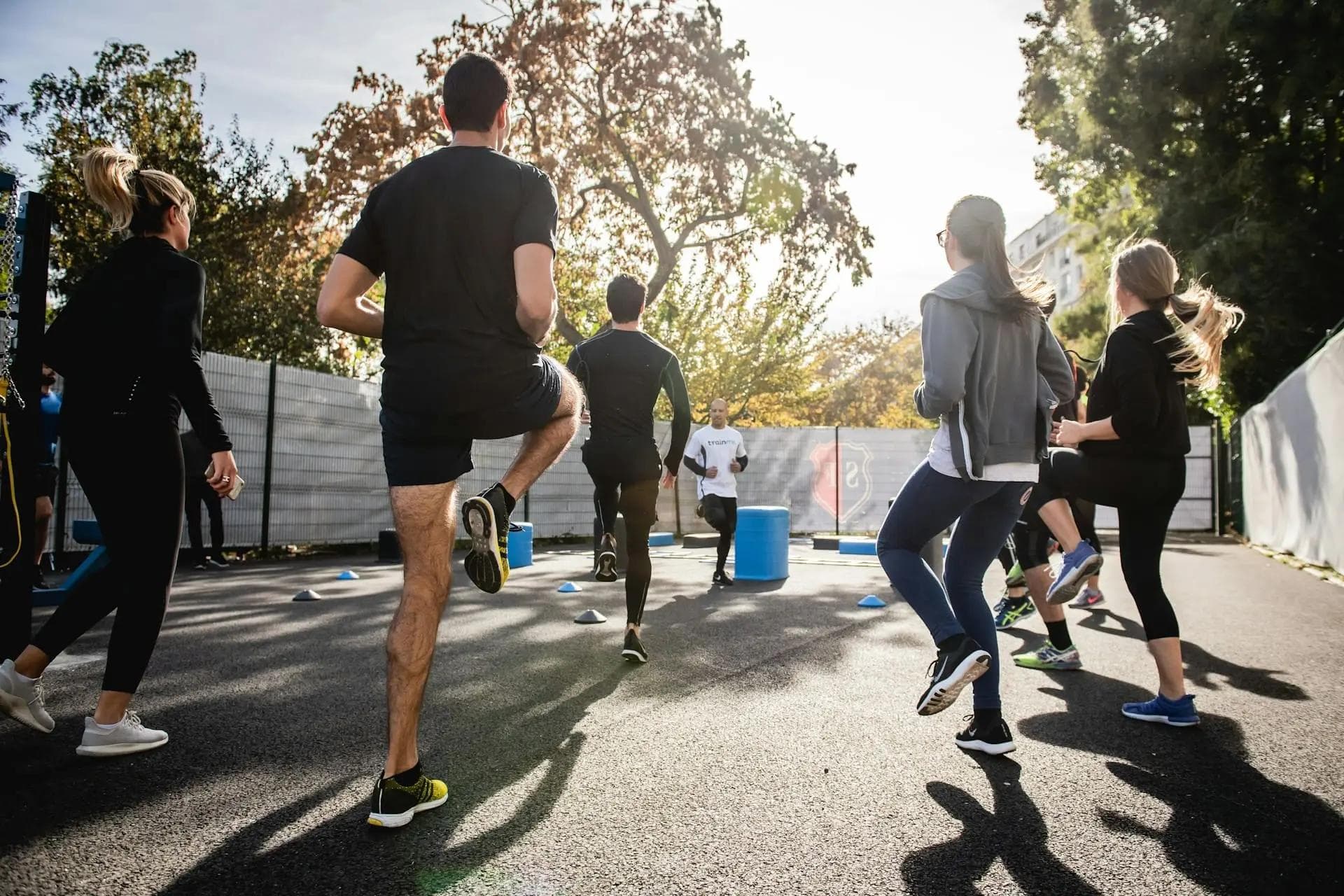Group of people exercising in a parking lot at sunrise with athletic clothing on